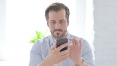Mature Man Celebrating Success on Smartphone