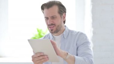 Mature Man having Loss on Tablet in Office 