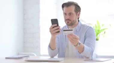 Happy Mature Man Shopping Online on Smartphone in Office 
