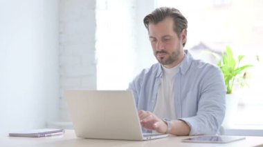 Mature Man Showing Thumbs Down While using Laptop 
