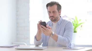 Mature Man using Smartphone in Office 