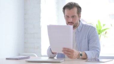 Mature Man Upset while Reading Documents in Office