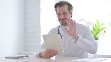 Male Doctor making Video Call on Tablet in Clinic