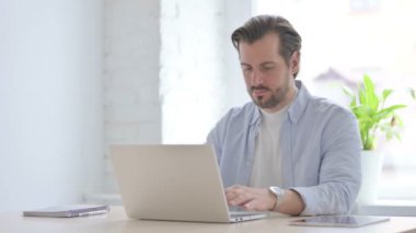 Busy Mature Man Typing on Laptop in Office
