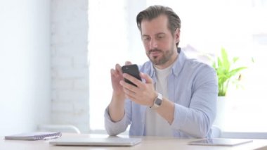 Upset Mature Man Reacting to Loss on Smartphone in Office 