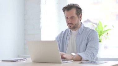 Mature Man Showing Thumbs Up While using Laptop 