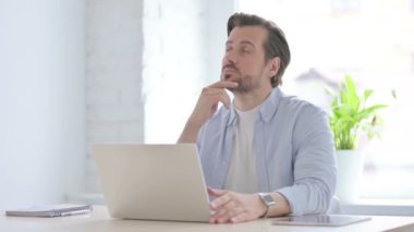 Mature Man Thinking while Working on Laptop
