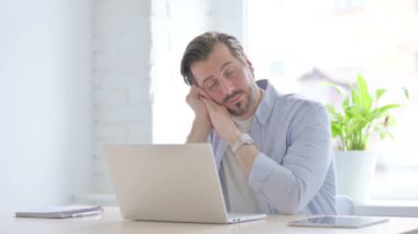 Mature Man with Laptop Taking Nap in Office