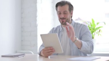 Mature Man Doing Video Call on Tablet in Office 