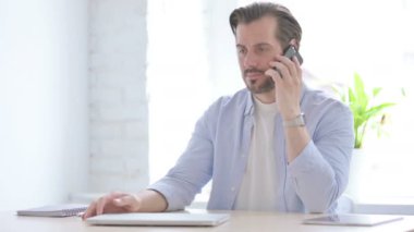 Mature Man Talking on Phone in Office 