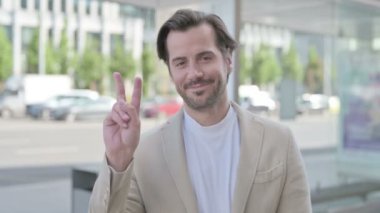 Outdoor Portrait of Man with Victory Sign 