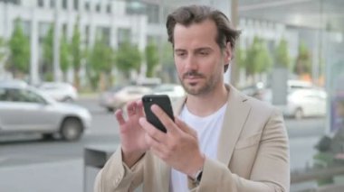 Man Reacting to Loss on Smartphone Outdoor 