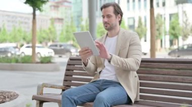 Man using Tablet while Sitting on Bench