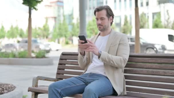 Man Browsing Internet Smartphone While Sitting Bench — Vídeos de Stock