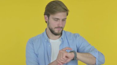 Casual Young Man Using Smartwatch on Yellow Background 