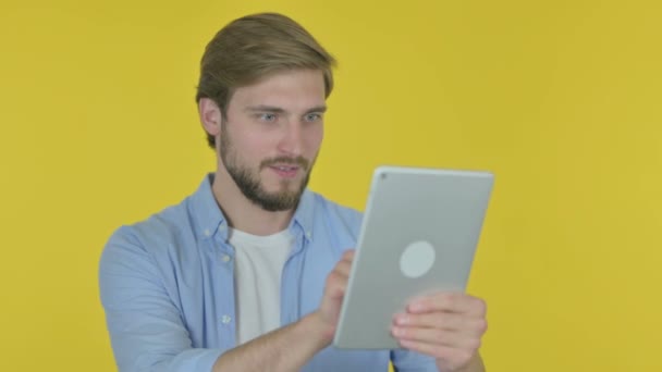 黄色の背景にタブレット上で成功を祝うカジュアル若い男 — ストック動画
