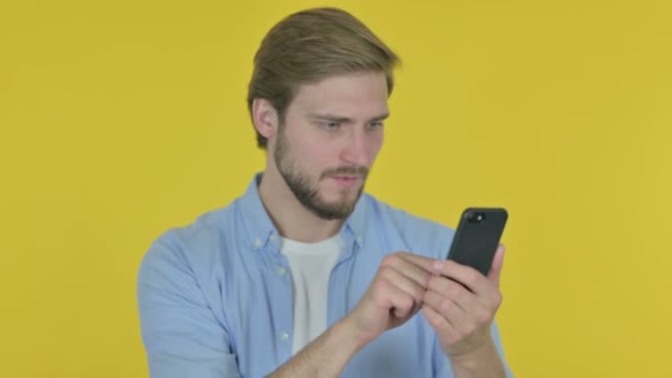 Casual Young Man Loss Smartphone Yellow Background — Stock video