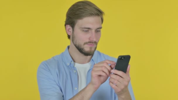 Casual Young Man Celebrating Smartphone Yellow Background — Stock video