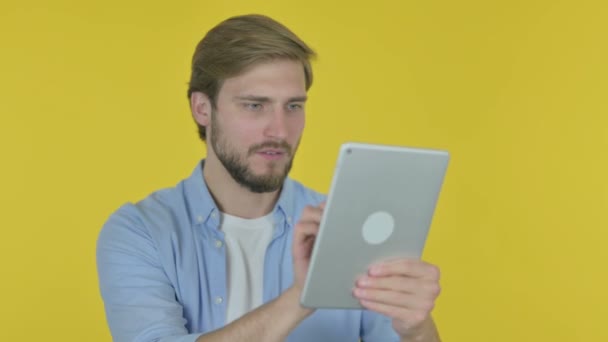 黄色の背景にタブレット上の損失に反応カジュアル若い男 — ストック動画