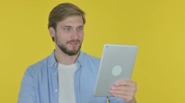 Video Call on Tablet by Casual Young Man on Yellow Background 