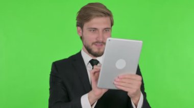 Young Adult Businessman Celebrating Success on Tablet on Green Background 