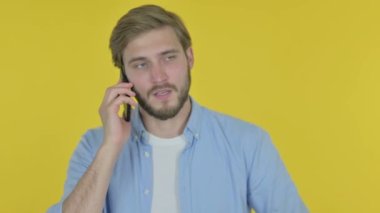 Casual genç adam konuşan üzerinde telefon sarı arka plan 