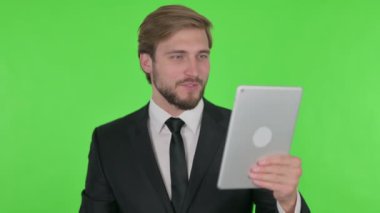 Video Call on Tablet by Young Adult Businessman on Green Background 