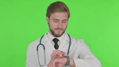 Young Adult Doctor Using Smartwatch on Green Background 