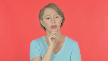Pensive Senior Old Woman Thinking and getting Idea on Red Background 