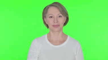 Senior Old Woman Pointing at the Camera on Green Background 