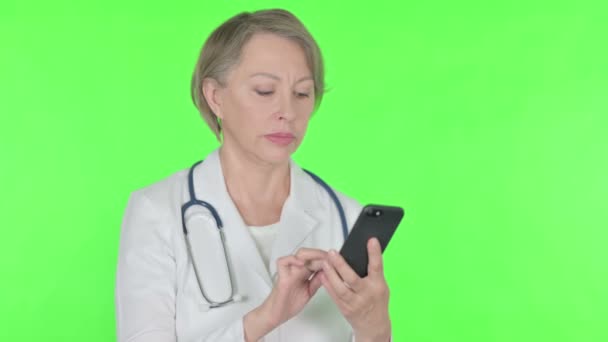 Senior Female Doctor Browsing Smartphone Green Background — 图库视频影像