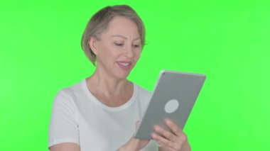 Senior Old Woman using Digital Tablet on Green Background 
