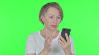 Senior Old Woman Loss on Smartphone on Green Background 