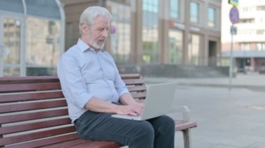 Senior Old Man with Laptop Looking at Camera while Sitting Outdoor on Bench