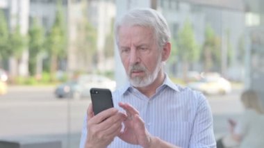 Upset Senior Old Man Reacting to Loss on Smartphone Outdoor
