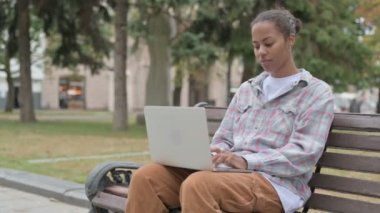 Young African Woman with Laptop Showing Thumbs Up Sign While Sitting Outdoor on Bench 