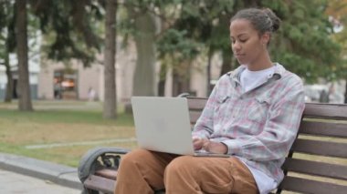 Young African Woman with Laptop Looking at Camera while Sitting Outdoor on Bench