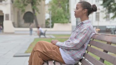 Young African Woman Looking at Camera while Sitting on Bench