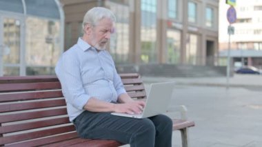 Senior Old Man with Back Pain Using Laptop while Sitting Outdoor on Bench