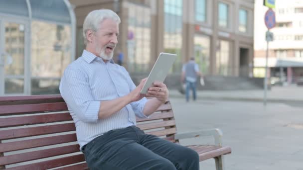 Senior Old Man Celebrating Online Win Tablet While Sitting Outdoor — Stockvideo