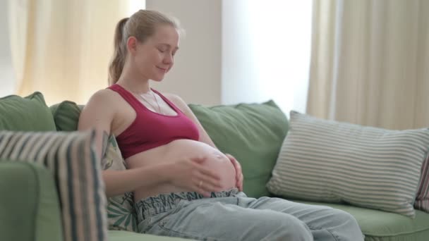 Pregnant Young Woman Stokes Her Big Belly While Sitting Sofa — Vídeos de Stock
