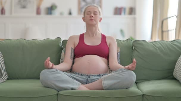Meditating Pregnant Young Woman Doing Yoga While Sitting Sofa — 图库视频影像