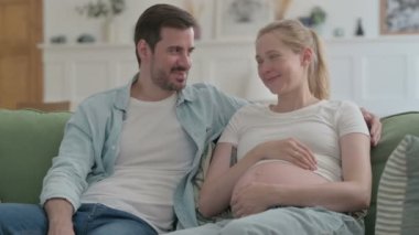 Happy Pregnant Young Couple Talking with Each other at Home