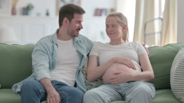 Pregnant Young Woman and Husband Talking with Each other at Home