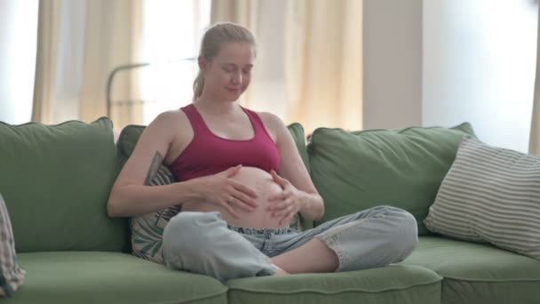 Happy Pregnant Young Woman Rubbing Her Big Belly While Sitting — Vídeo de Stock