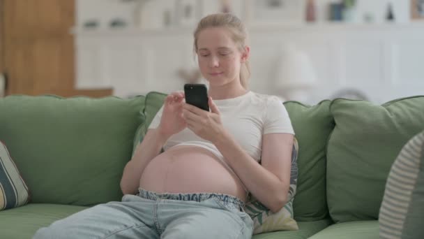 Pregnant Young Woman Browsing Smartphone While Sitting Sofa — 图库视频影像