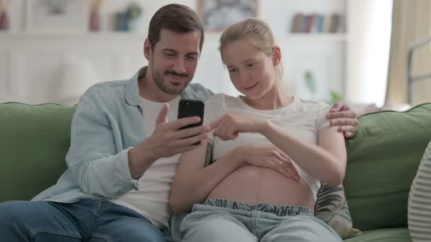 Pregnant Young Couple Browsing Smartphone Home — Vídeo de Stock