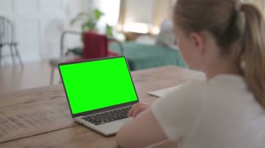 Rear View of Young Woman Working on Laptop with Green Chroma Screen 