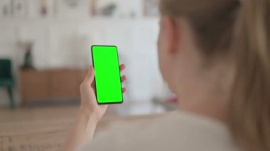 Rear View of Young Woman using Smartphone with Green Chroma Screen 