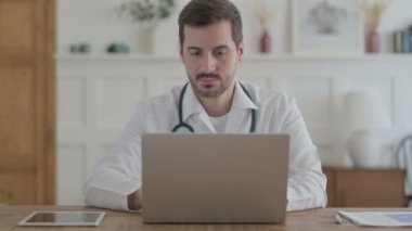 Klinikte dizüstü bilgisayarda çalışan erkek doktor.